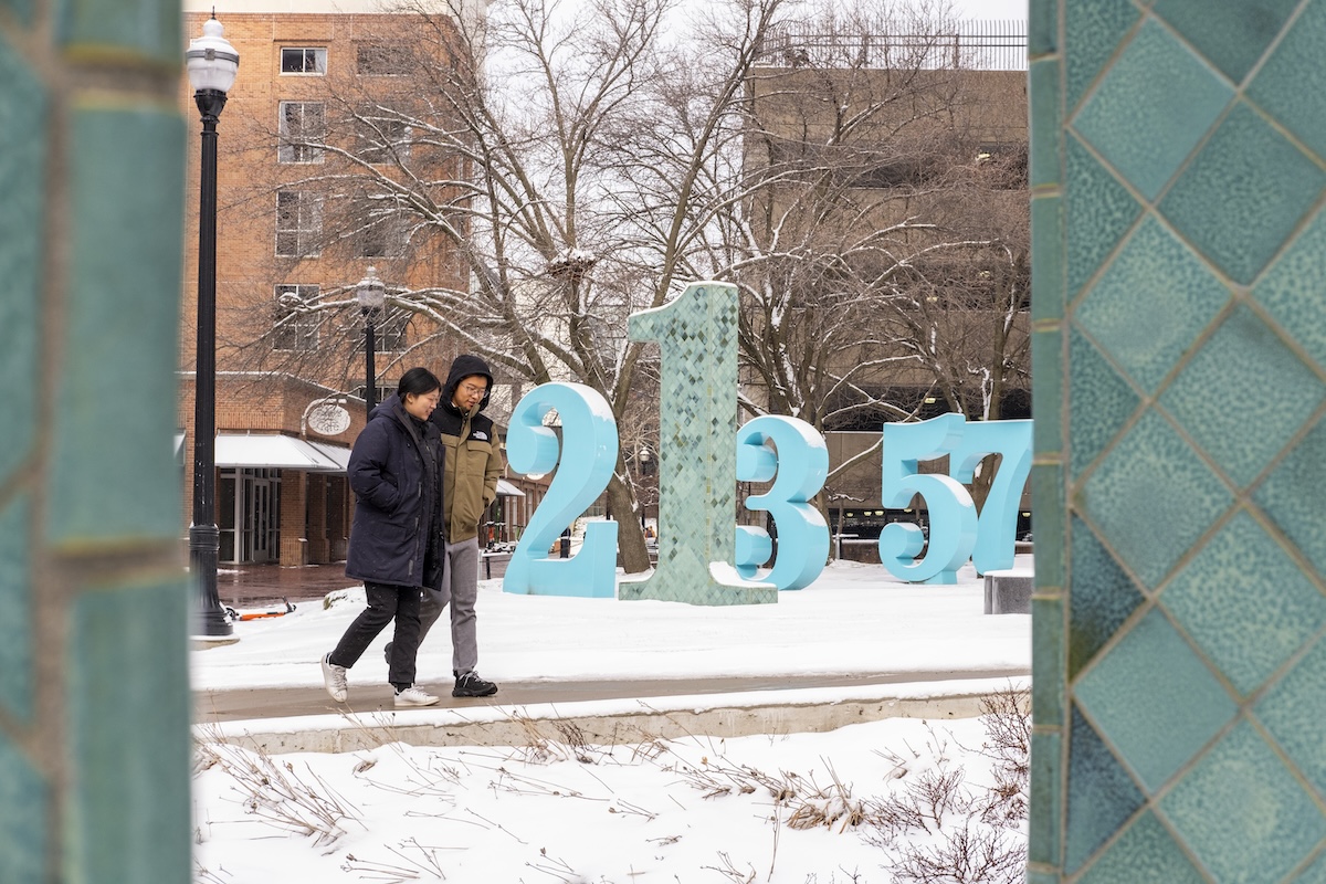 Two students walk through campus on a snowy day.