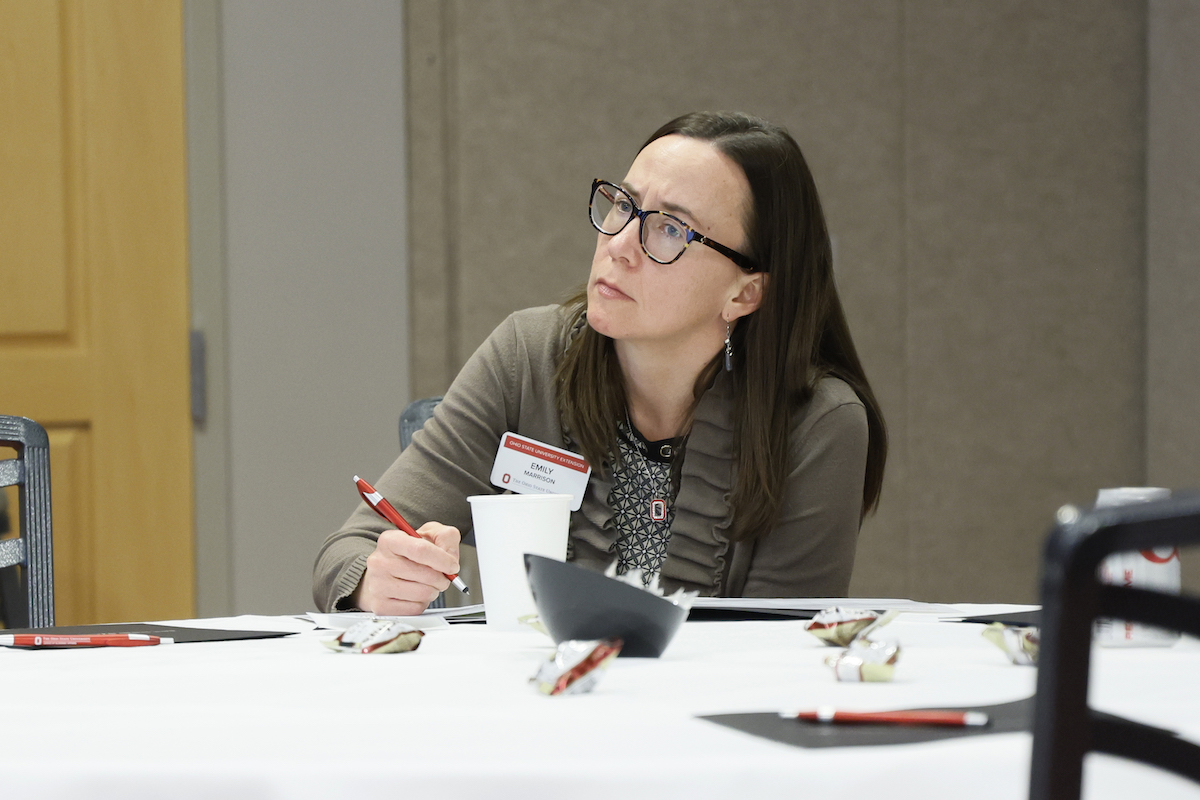 A young woman is seated taking notes during New Faculty Orientation.