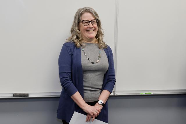 Susan Cole stands in front of a classroom whiteboard.
