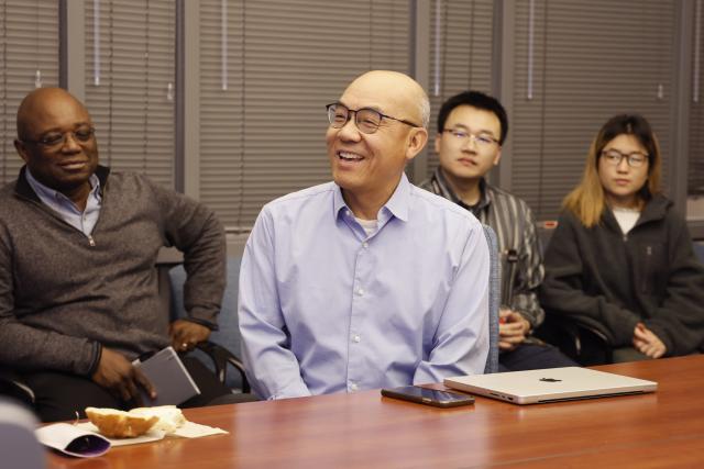 Shan-Lu Liu sits at a confernence table with colleagues in the background