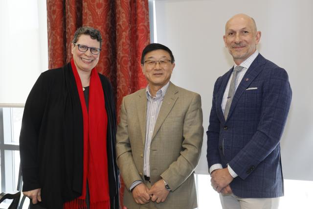 Alan Luo stands with two university leaders