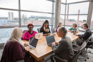 A group of staff collaborate around a table in a conference room.